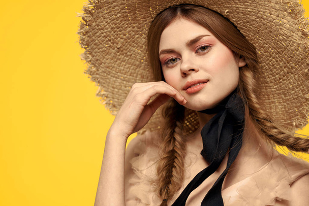 黄色の背景に藁帽子の肖像画の女性は夏のドレスモデルのピグテールロマンスのクロップドビュー - 写真・画像