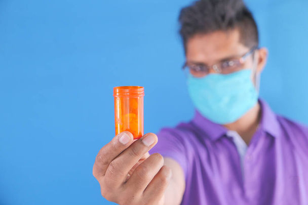 junger Mann mit Mundschutz hält Tablettenbehälter mit Kopierplatz  - Foto, Bild