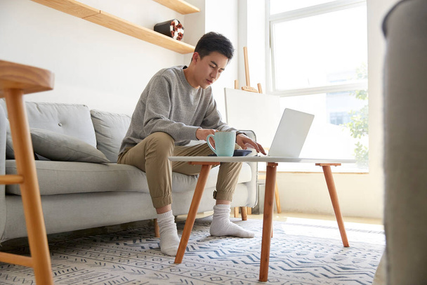 junge asiatische Führungskräfte bleiben zu Hause und arbeiten mit Laptop-Computer - Foto, Bild
