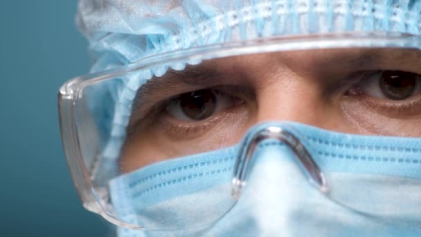 Doktorze Buźka, oczy w okularach ochronnych. Portret medyczny Mężczyzna noszący ochronę i okulary w szpitalu lub klinice podczas Covid 19. Pracownik służby zdrowia patrzący w kamerę. Powieść Coronavirus 2019-nCoV - Materiał filmowy, wideo