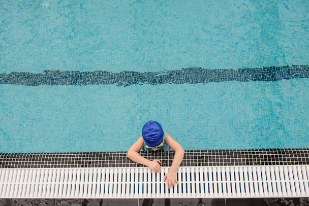 вид зверху на 7-річного хлопчика, який грає і плаває в басейні
 - Фото, зображення