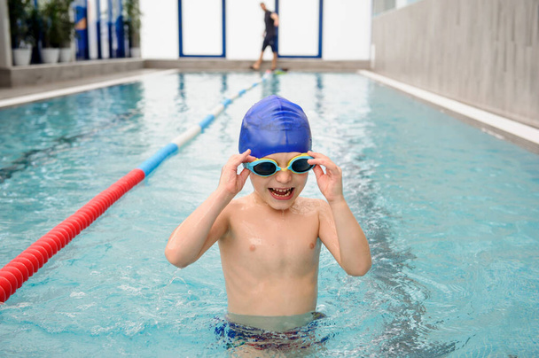 幸せな7歳の男の子がプールで遊んで泳いだり笑ったりしています - 写真・画像
