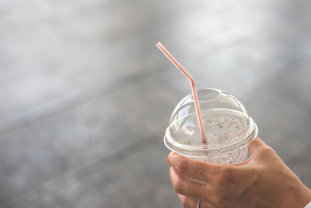 Hand holding a smoothie with a straw. - Фото, зображення
