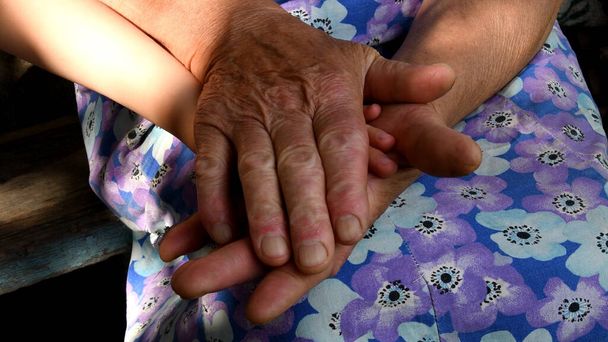 La donna anziana tiene la mano del bambino dalle sue mani rugose invecchiate. Mani diverse di 4 anni e 80 anni. Concetto di amore e solidarietà della famiglia multigenerazionale - Foto, immagini
