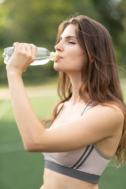 Girl athlete drinks water during a break in sports - Fotoğraf, Görsel