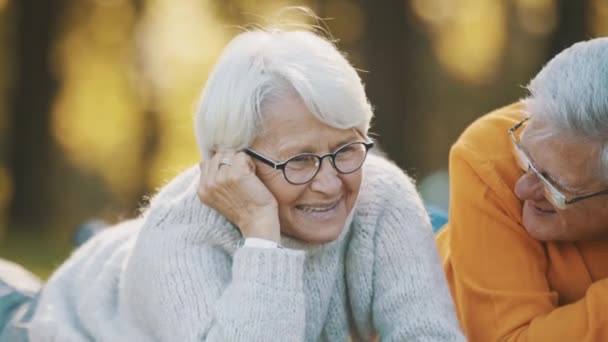Romantik im Alter. Rentnerpaar genießt Herbstpicknick. Auf dem Tisch liegen und einander anschauen - Filmmaterial, Video