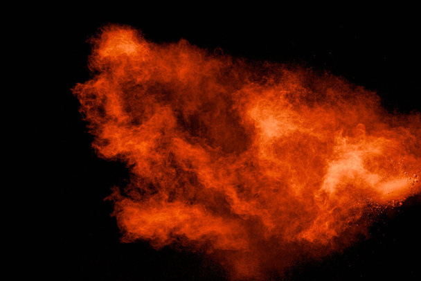 Abstract explosion of orange dust on black background.Freeze motion of orange powder burst. - Photo, Image