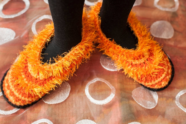 Μια γυναίκα ζεσταίνει τα πόδια της με παντόφλες. Η μητέρα της έφτιαξε τις παντόφλες της - Φωτογραφία, εικόνα