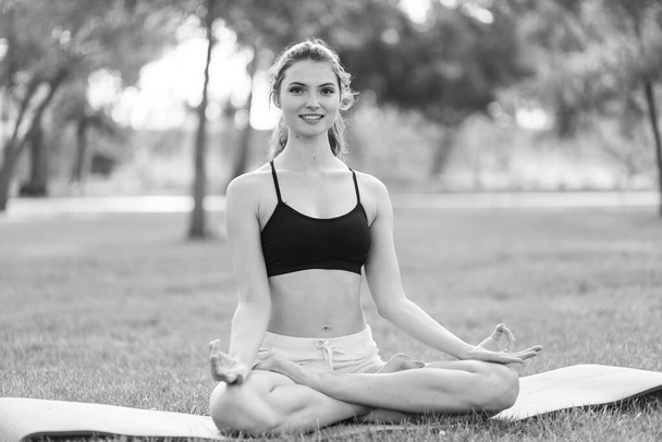 Girl doing yoga in the park during the day. Black and white photo. BW - Фото, зображення