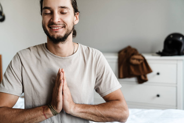 Young man meditating in bedroom in the morning - Foto, imagen