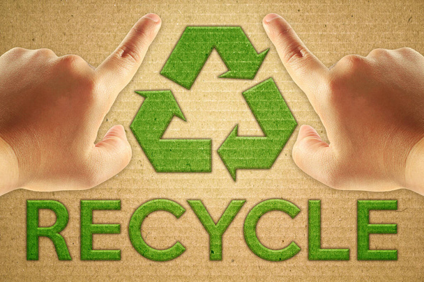 Reciclar el símbolo verde en cartón con el reciclado de texto y el punto de enfoque mano hombre. - Foto, imagen