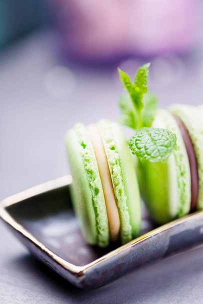 Hausgemachte französische grüne Makronen oder Macarons. Minzkekse mit Schokolade und Vanillecreme auf grauem Hintergrund. Kopierraum - Foto, Bild