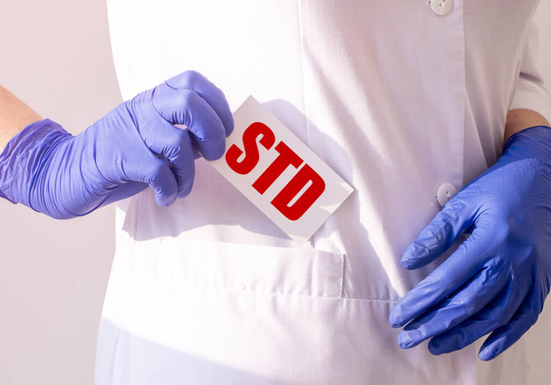 STD acronym word on paper card in hand of doctor in protective glove, sexually transmitted disease concept - Foto, immagini