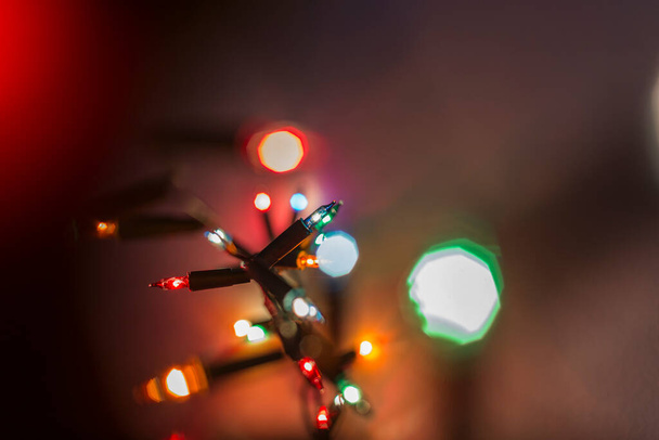 kis színes izzók közelsége, karácsonyfa dekorációk, háttérvilágítás elmosódott - Fotó, kép