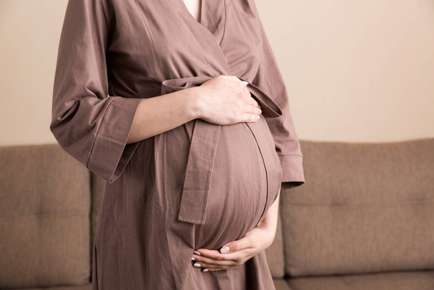 Embarazo mujer en hermoso vestido de pie en el hogar. - Foto, imagen