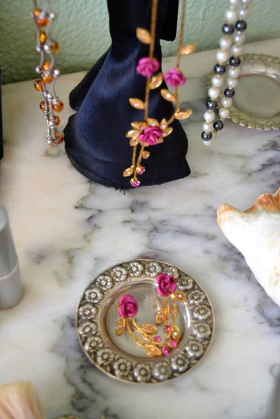 Woman's dressing table with a mannequin for hanging necklaces, makeup brushes, earrings, lipsticks and a flower-shaped brooch on a marble table - Photo, Image