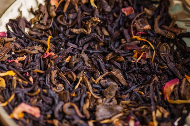 Grüner Tee mit Rose. Aromatisierte schwarze, getrocknete Teemischung mit Rosenblättern. eine Mischung aus schwarzem und grünem Tee mit dem Zusatz von Kornblumen- und Teerosenblüten. trockene Teeblätter - Foto, Bild