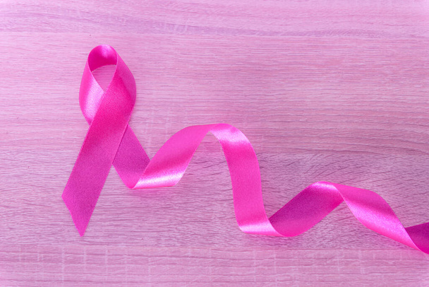 Růžová stuha na světle růžové dřevěné pozadí, symbol povědomí o rakovině prsu a říjen Růžový den pozadí, světový den rakoviny. - Fotografie, Obrázek