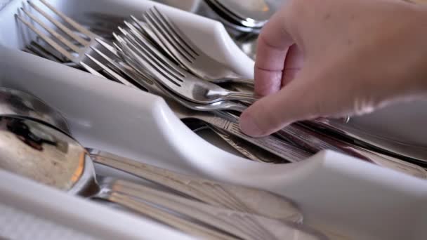 Mano femminile mette un cucchiaio e forchette in scatola con posate sporche sulla cucina domestica - Filmati, video