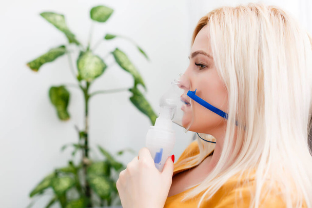 Young woman using nebulizer for asthma and respiratory diseases home - Photo, Image