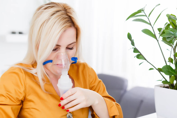 Молодая женщина использует туманность при астме и респираторных заболеваниях дома - Фото, изображение