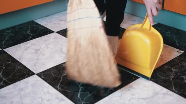 Funny Woman Dances and Sweeps Πάτωμα στις Κάλτσες στην κουζίνα με σκούφο και φτυάρι - Πλάνα, βίντεο