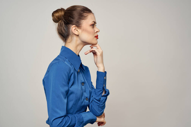 Eine elegante Dame im blauen Hemd gestikuliert mit ihren Händen auf hellem Hintergrund und einem Nahaufnahme-Porträt aus dem Kopierraum - Foto, Bild