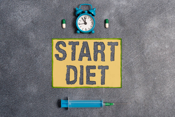 Tekst pisania słów Start Dieta. Koncepcja biznesowa dotycząca praktyki spożywania żywności w sposób regulowany i nadzorowany Zestaw sprzętu medycznego z notatnikiem do oceny stanu zdrowia. - Zdjęcie, obraz
