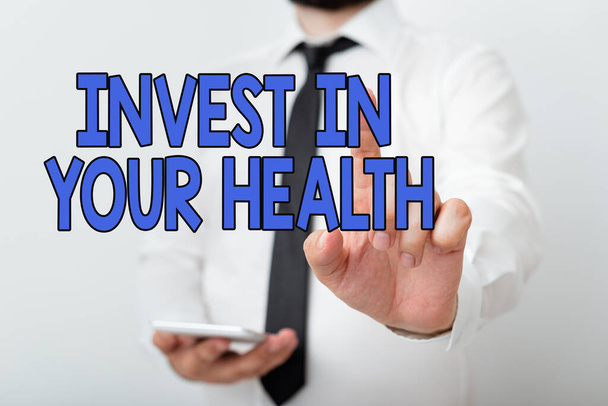 健康への投資を示すテキスト記号。ナビゲーションの進歩を象徴する手の指を指すとあなたの健康モデルの維持または改善にお金を置く概念的な写真. - 写真・画像