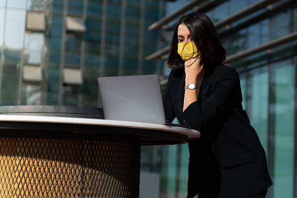 Молодая бизнесвумен носит маску для защиты от вирусов в городе. - Фото, изображение