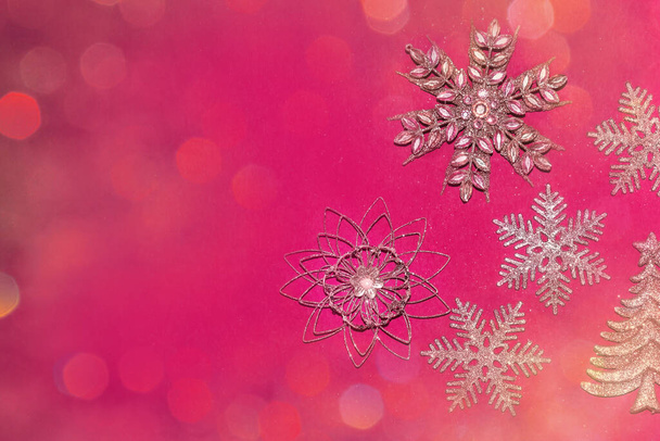 Элегантный розовый рождественский фон с блестящими золотыми снежинками с боке - Фото, изображение