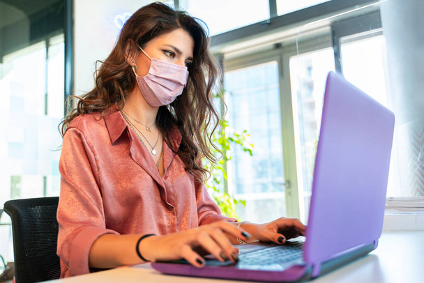 Frau arbeitet wegen Pandemie mit Maske - Foto, Bild