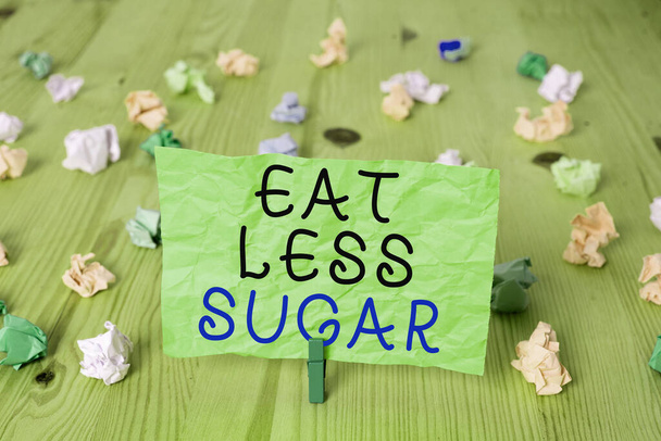 Текст слова "Ешь меньше сахара". Бизнес-концепция сокращения потребления сахара и здорового питания богатые пищевые продукты Цветные мятые прямоугольник форме напоминания бумаги светло-голубой фон. - Фото, изображение