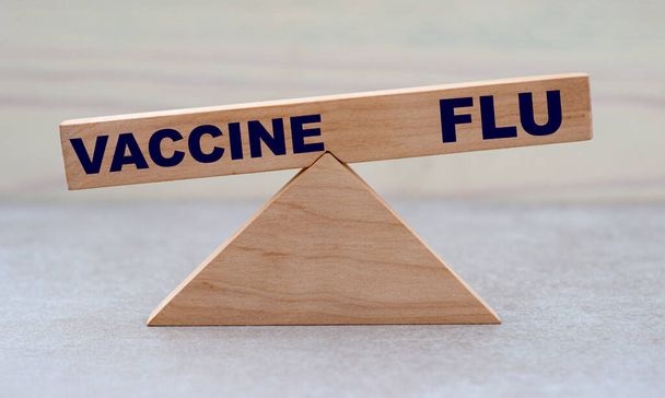 concept of the balance of words vaccine and flu on wooden scales - Zdjęcie, obraz