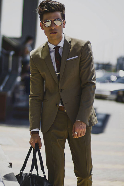 Handsome man in a suit wearing sunglasses and with a bag - Photo, Image