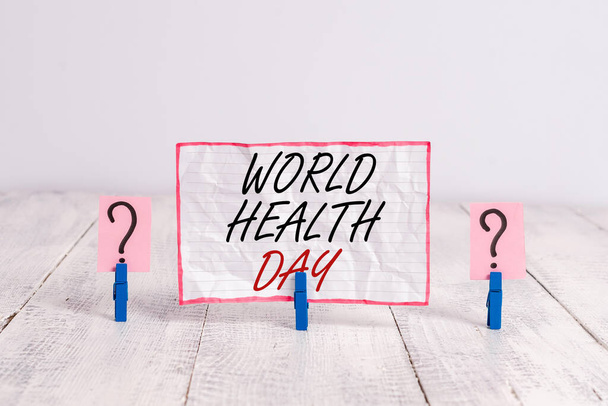 Handwriting text World Health Day. Concept meaning global health awareness day celebrated every year on 7 April Scribbled and crumbling sheet with paper clips placed on the wooden table. - Photo, Image