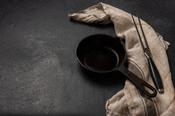Empty black cast iron frying pan on a dark graphite background - Photo, image