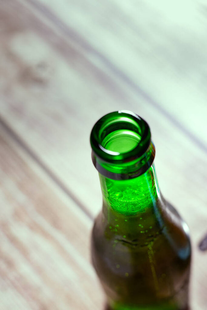 Zielona butelka piwa otwarta na drewnianej powierzchni jeszcze bliżej - Zdjęcie, obraz