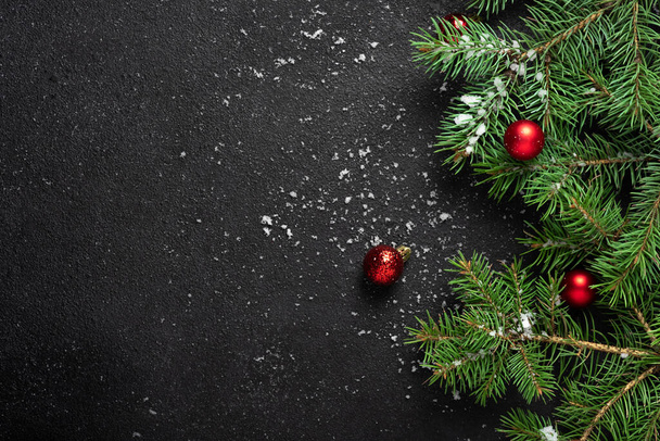 Christmas or New Year decoration background. For fir tree branches on black background with copy space. Flat lay. Pattern. White snowflakes and snow, red balls. - Fotoğraf, Görsel