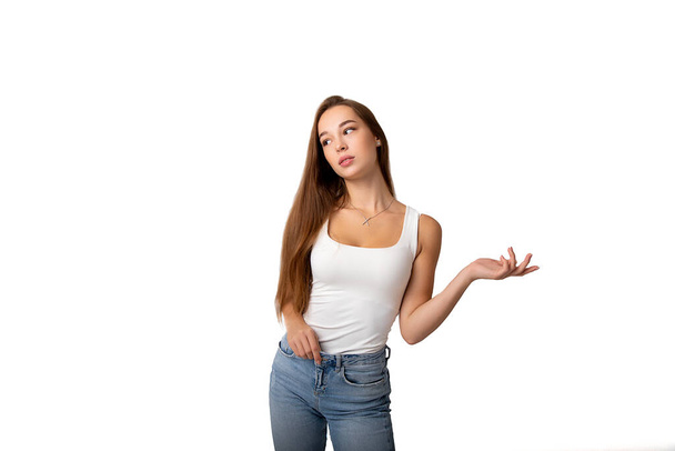 カジュアルな服のシャツやジーンズで美しい白人の長い髪の若い女性は、オープン手の手のひらに空のコピースペースを示しています。スタジオショット - 写真・画像
