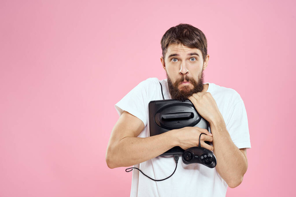 Muž s předponou v ruce joystick hry životní styl zábava růžové pozadí bílé tričko - Fotografie, Obrázek