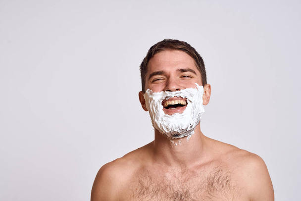 Bonito homem com espuma de barbear branco em seu rosto e pele limpa com barbear grooming ombros nus - Foto, Imagem