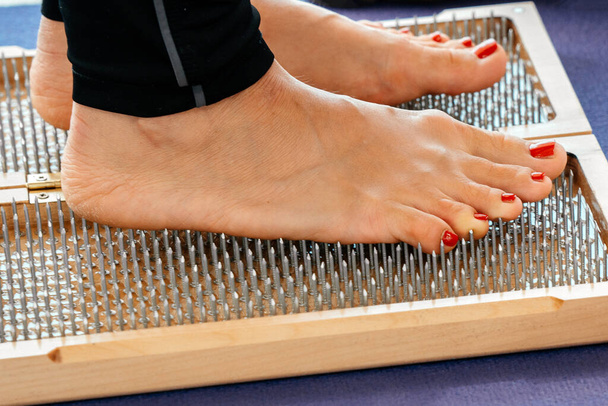 Nahaufnahme einer Yoga-Person, die mit scharfen Nägeln auf einem Sadhu-Brett steht - Foto, Bild