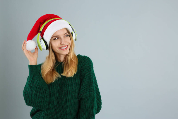 Happy woman with headphones on grey background, space for text. Christmas music - Valokuva, kuva