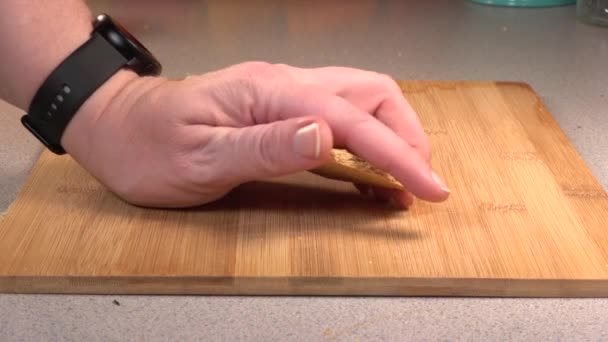 Head crushes graham cracker in slow motion over a wood cutting board - Filmati, video