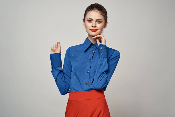 Una elegante dama de camisa azul hace gestos con las manos sobre un fondo claro y un retrato de primer plano - Foto, imagen
