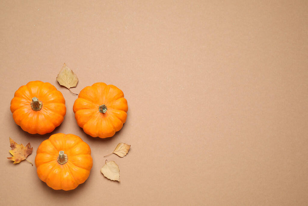 Fresh ripe pumpkins and autumn leaves on brown background, flat lay. Space for text - Фото, зображення