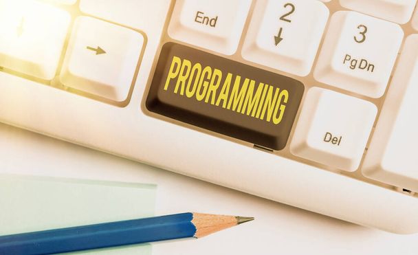 Text sign showing Programming. Conceptual photo the process of preparing an instructional program for a device Different colored keyboard key with accessories arranged on empty copy space. - Photo, Image
