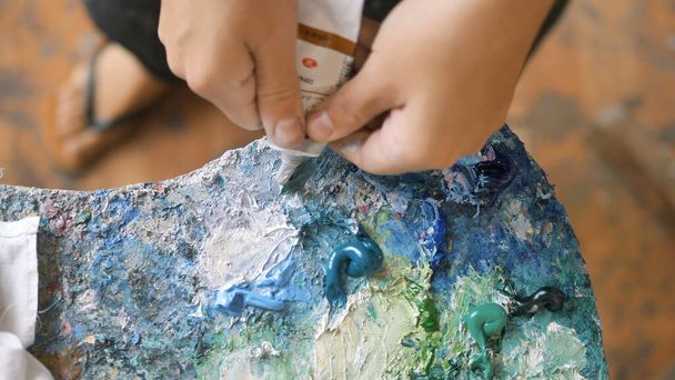 Woman squeezes out white paint on palette with colors close - Photo, Image