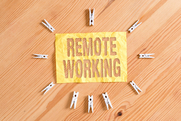 Writing note showing Remote Working. Business photo showcasing style that allows professionals to work outside of an office Colored clothespin papers empty reminder wooden floor background office. - Photo, Image